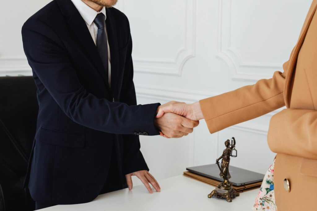 Two business professionals shaking hands in an office, showcasing agreement.